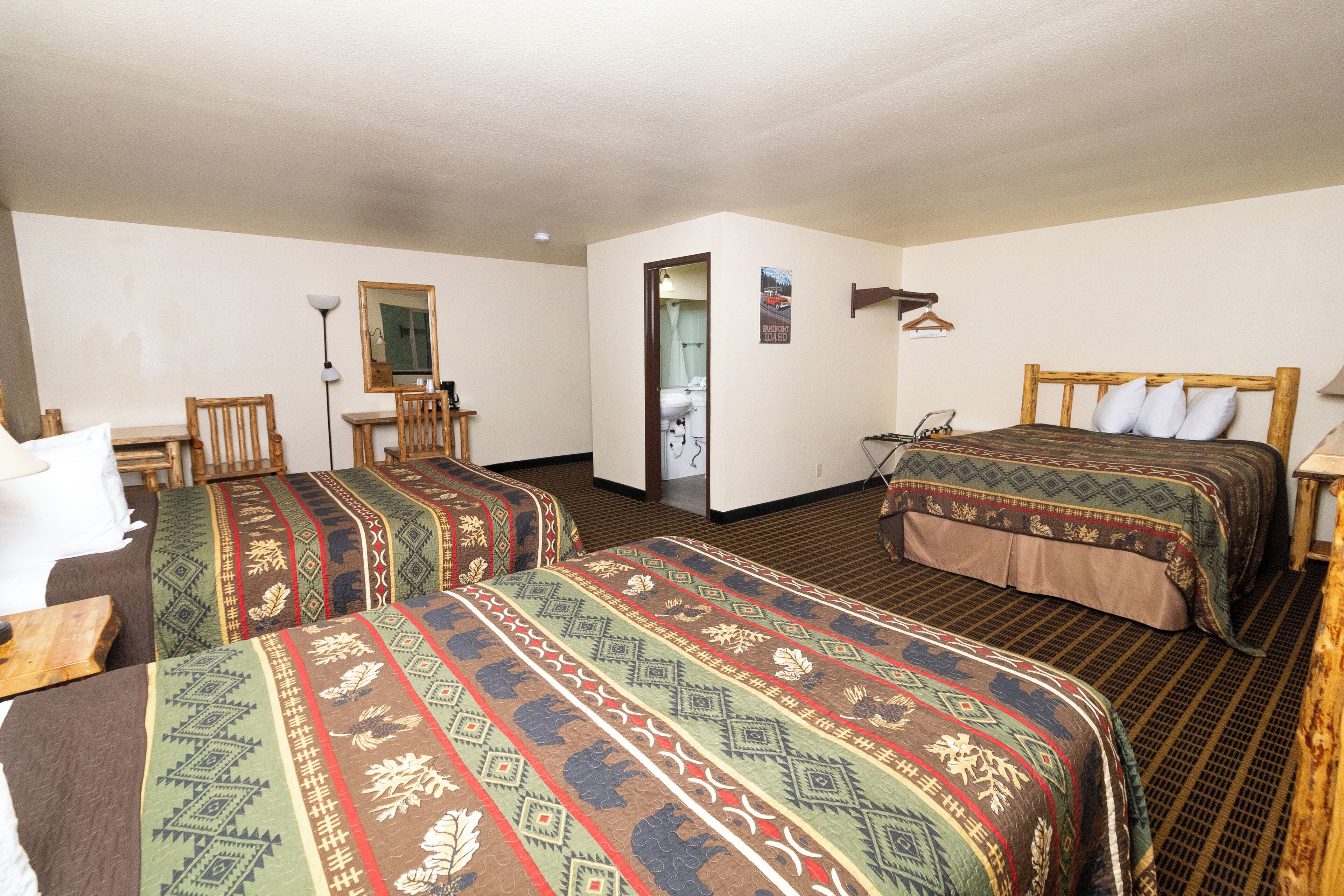 Una habitación de hotel con dos camas, un escritorio, una silla y un espejo.