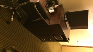 A hotel room with a bed, a desk, and a television.