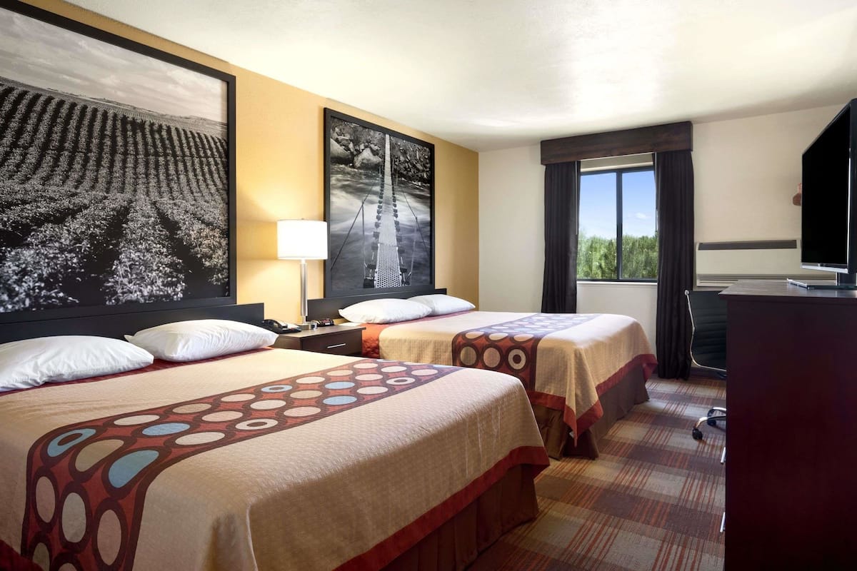 Une chambre d’hôtel avec deux lits, un bureau, une télévision et une grande fenêtre.