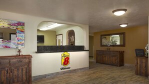 A reception area with a 'Super 8' logo, wooden cabinets, a marble counter, and a mirror above it.