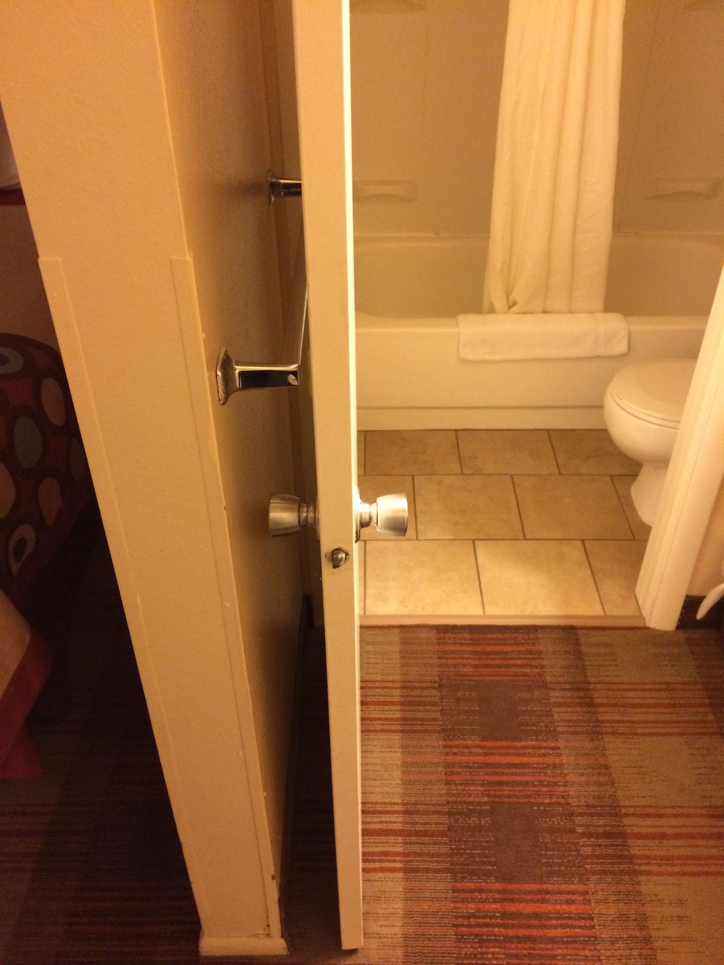 A bathroom with a toilet, a shower, and a door leading to another room.
