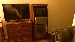 A living room with a wooden coffee table, a green sofa, a wooden cabinet, and a television.