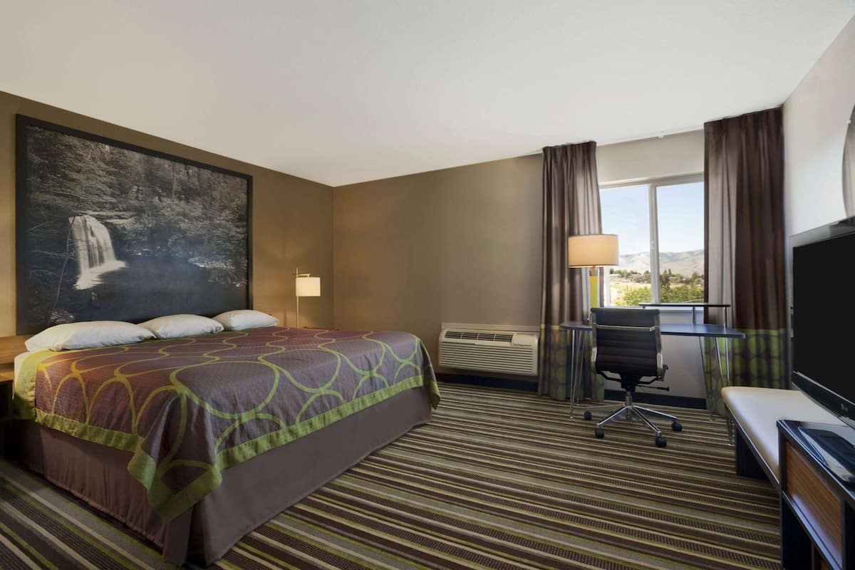Een hotelkamer met een groot bed, een bureau, een stoel en een televisie.
