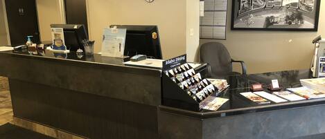 A hotel reception desk with a digital screen, a sign for Idaho Dining, and a framed welcome sign.