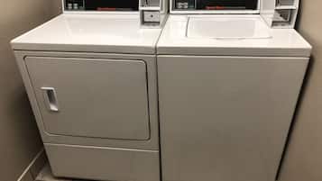 Two white commercial washers with digital displays, one labeled "Speed Queen Commercial Dryer" and the other "Speed Queen Commercial Washer."