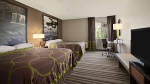 A hotel room with two beds, a desk with a TV, a chair, and a window with curtains.