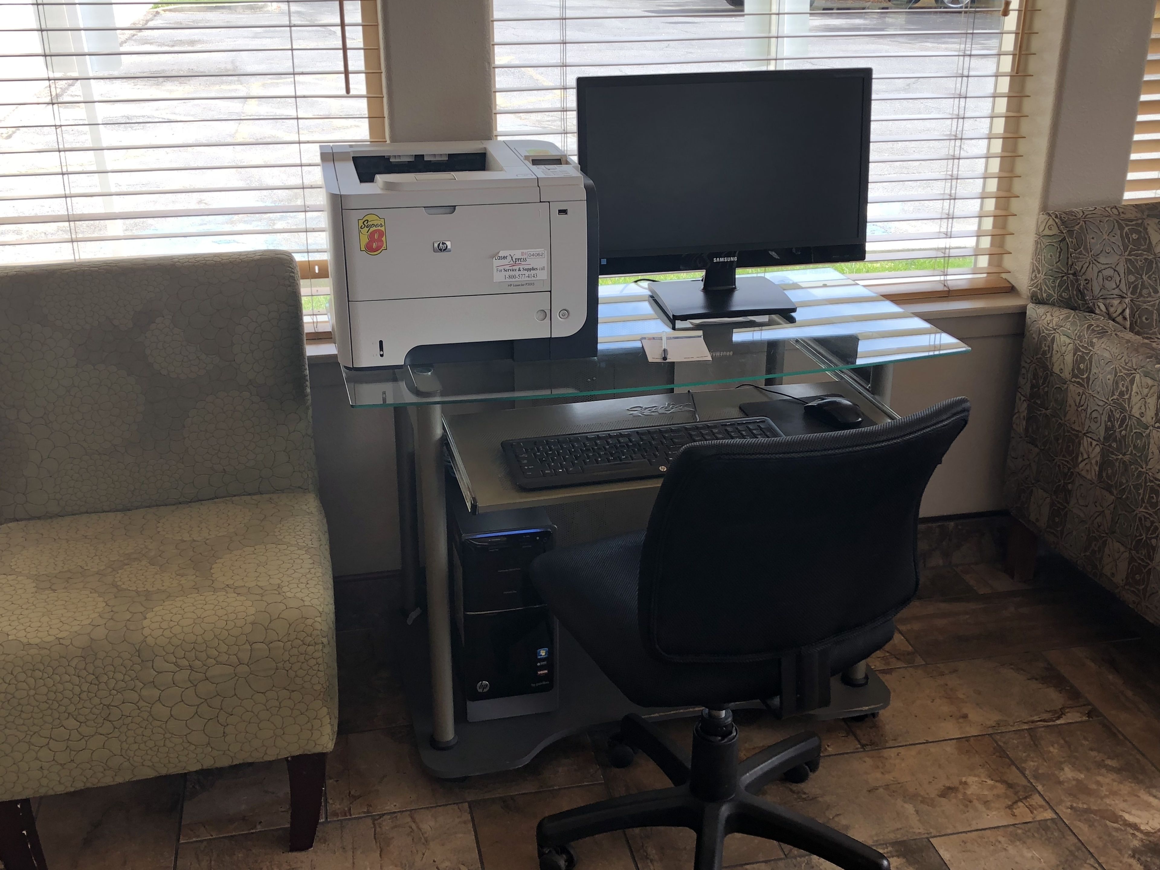 A home office setup with a desktop computer, printer, and office chair.