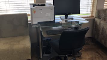 A home office setup with a desktop computer, printer, and office chair.