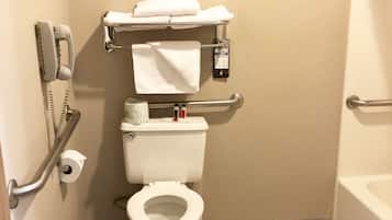 Un baño pequeño para una sola persona, con inodoro, barandilla y teléfono.
