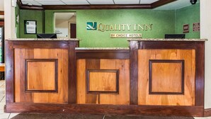 A reception desk with a green wall and a sign that reads "Quality Inn by Choice Hotels". - Quality Inn South (Indianapolis)