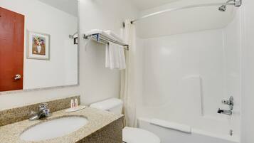 A bathroom with a granite sink, a toilet, a shower with a glass door, and a framed picture on the wall.