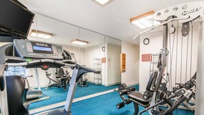A gym with a treadmill, weight machines, and a mirrored wall. - Quality Inn South (Indianapolis)