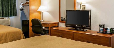 Une chambre d’hôtel équipée d’un lit, d’un bureau avec une chaise, d’une télévision, d’un miroir et d’une machine à café.