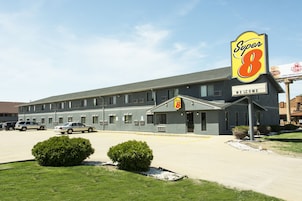 Un motel con un letrero de 'Super 8', un estacionamiento y un cartel de 'Welcome'.