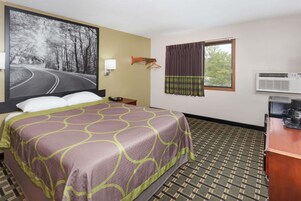 Habitación de hotel con una cama, un cuadro grande de una carretera, un equipo de aire acondicionado y una ventana con cortinas.