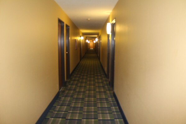 A hotel hallway with a checkered floor and doors on both sides. - Super 8 by Wyndham Michigan City (Michigan City)