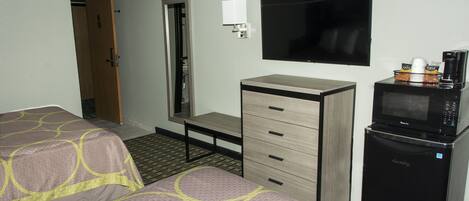 Habitación de hotel con dos camas, un escritorio, un televisor, un microondas y una cafetera.
