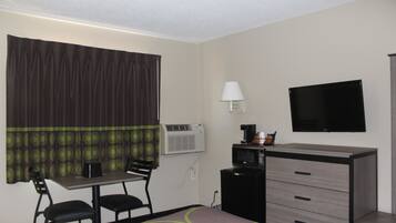 Une chambre d’hôtel comprenant un lit, un bureau avec une chaise, une télévision, une lampe et un mini-bar.