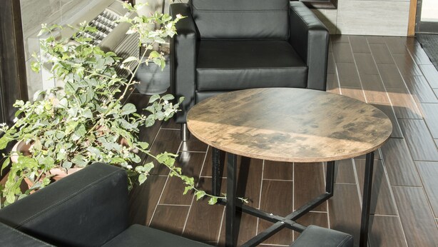 Un interior moderno con un sofá de cuero negro, una mesa redonda y una planta en maceta.