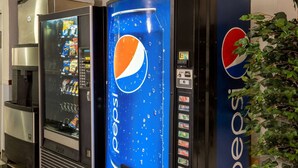 Deux distributeurs automatiques arborant le logo Pepsi, l’un doté d’une vitrine en verre et l’autre d’un fond bleu.