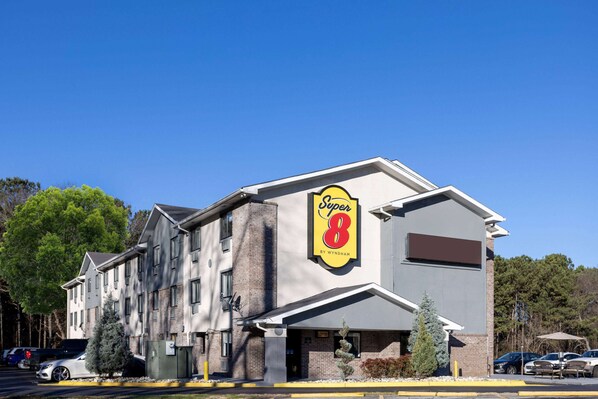 A Super 8 hotel with a prominent sign, brick facade, and a parking lot with several cars.