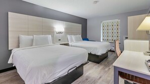 A hotel room with two beds, a desk, and a window with patterned curtains. - Days Inn by Wyndham Savannah Gateway I-95 (Savannah)