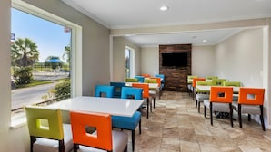 A restaurant with multiple tables and chairs, a stone fireplace, and a view of the street. - Days Inn by Wyndham Savannah Gateway I-95 (Savannah)