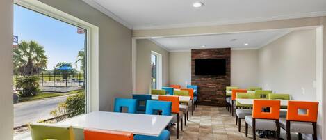 A restaurant with multiple tables and chairs, a stone fireplace, and a view of the street.