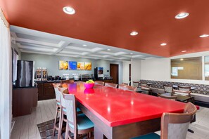 A spacious dining area with a red table, wooden chairs, and a kitchen in the background. - Comfort Inn & Suites Springfield I-55 (Springfield)