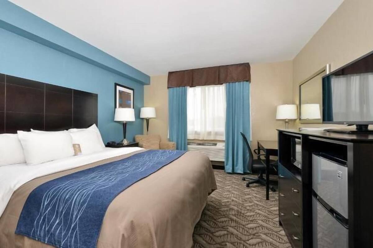A hotel room with a bed, desk, and TV.