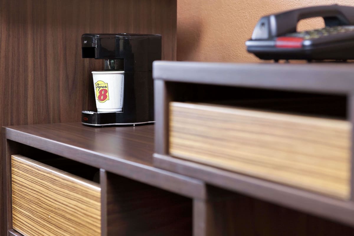 A coffee maker and a phone on a wooden counter.