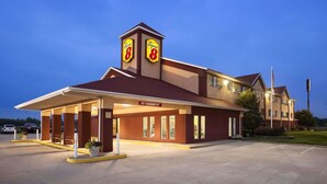 Un hotel con entrada cubierta, un cartel que indica 15 centímetros de altura libre y el logotipo de Super 8.