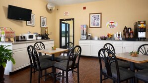 Un restaurante con mostrador, sillas, televisor y máquina de café.