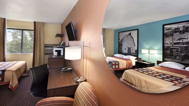 Habitación de hotel con dos camas, un escritorio, una silla, un televisor y un espejo.