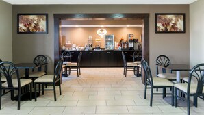 A restaurant with a counter, chairs, and framed artwork on the walls. - Super 8 by Wyndham Springfield East (Springfield)