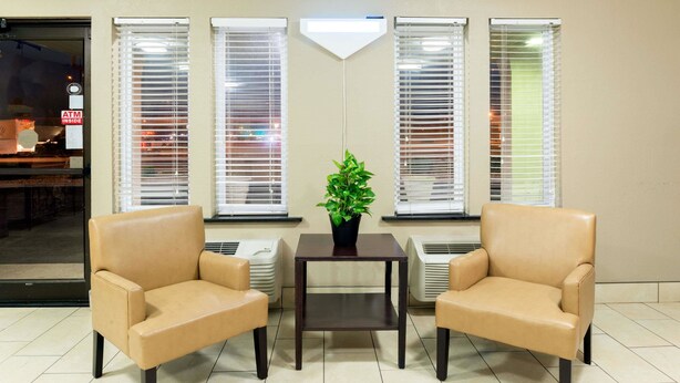 A waiting area with two beige armchairs, a small table, and a potted plant. - Super 8 by Wyndham Springfield East (Springfield)