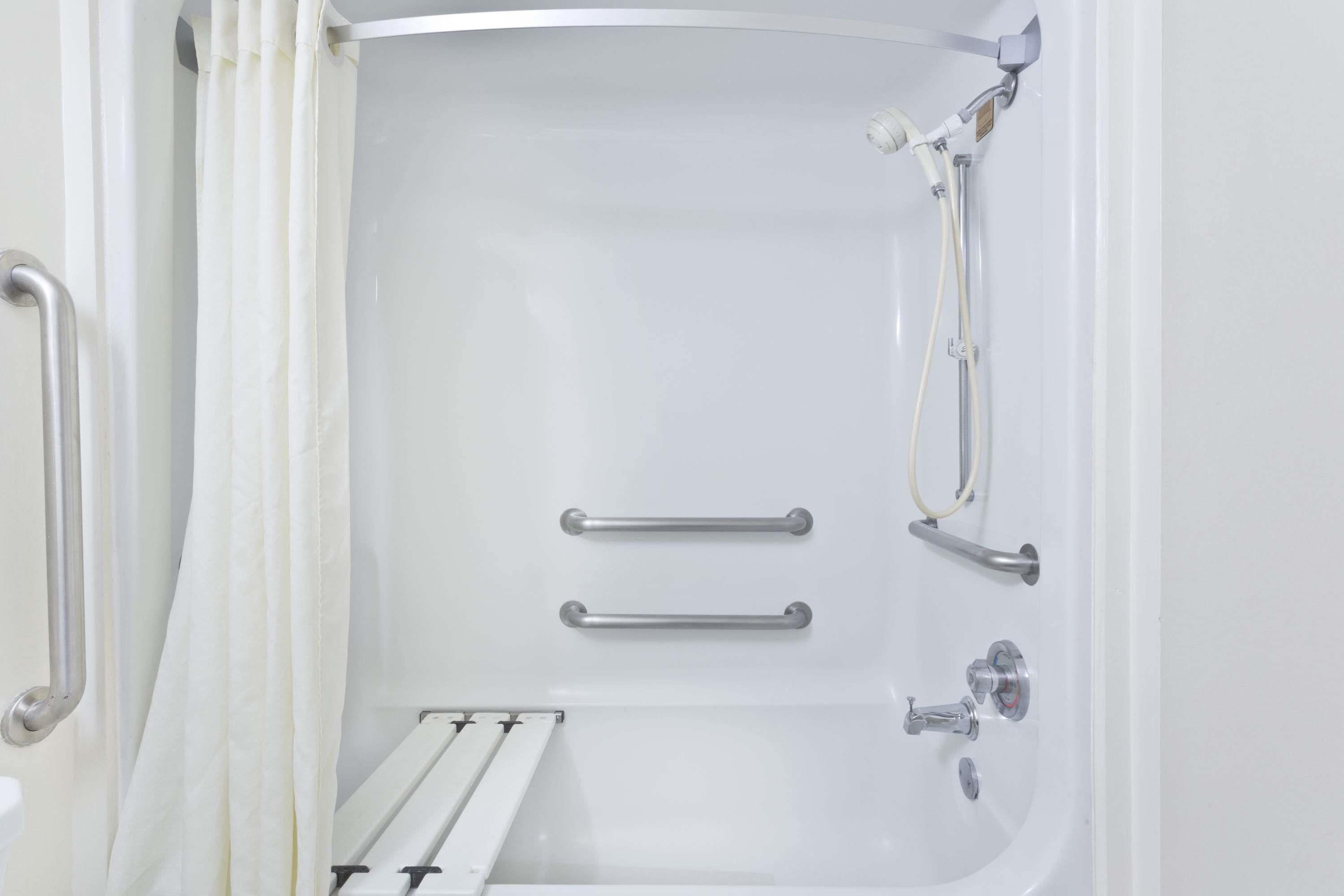 Un baño moderno con bañera, barras de apoyo y ducha.