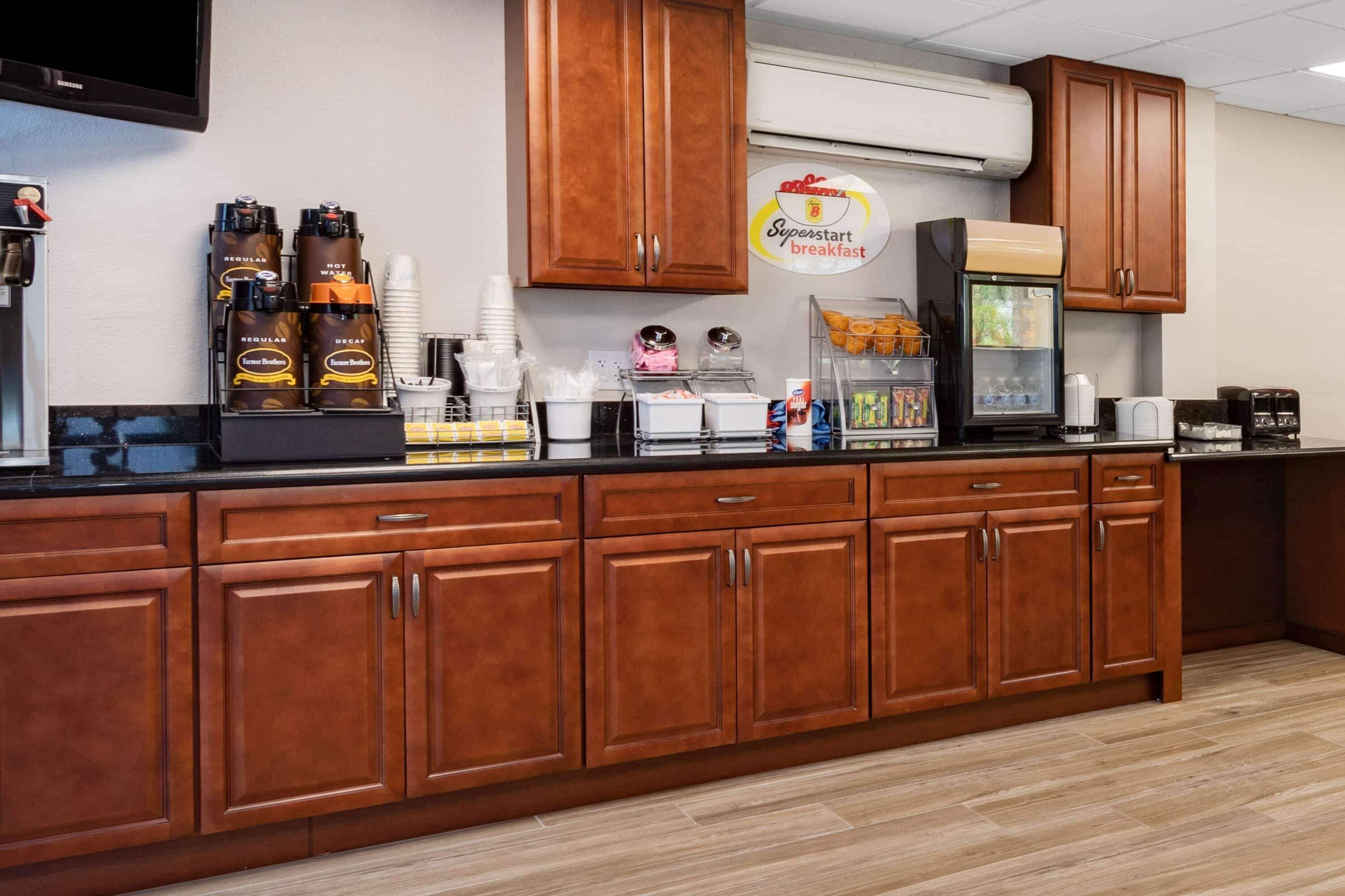Een ontbijtbuffet met koffieautomaten, een bord met de tekst Superstart breakfast en drankdispensers.