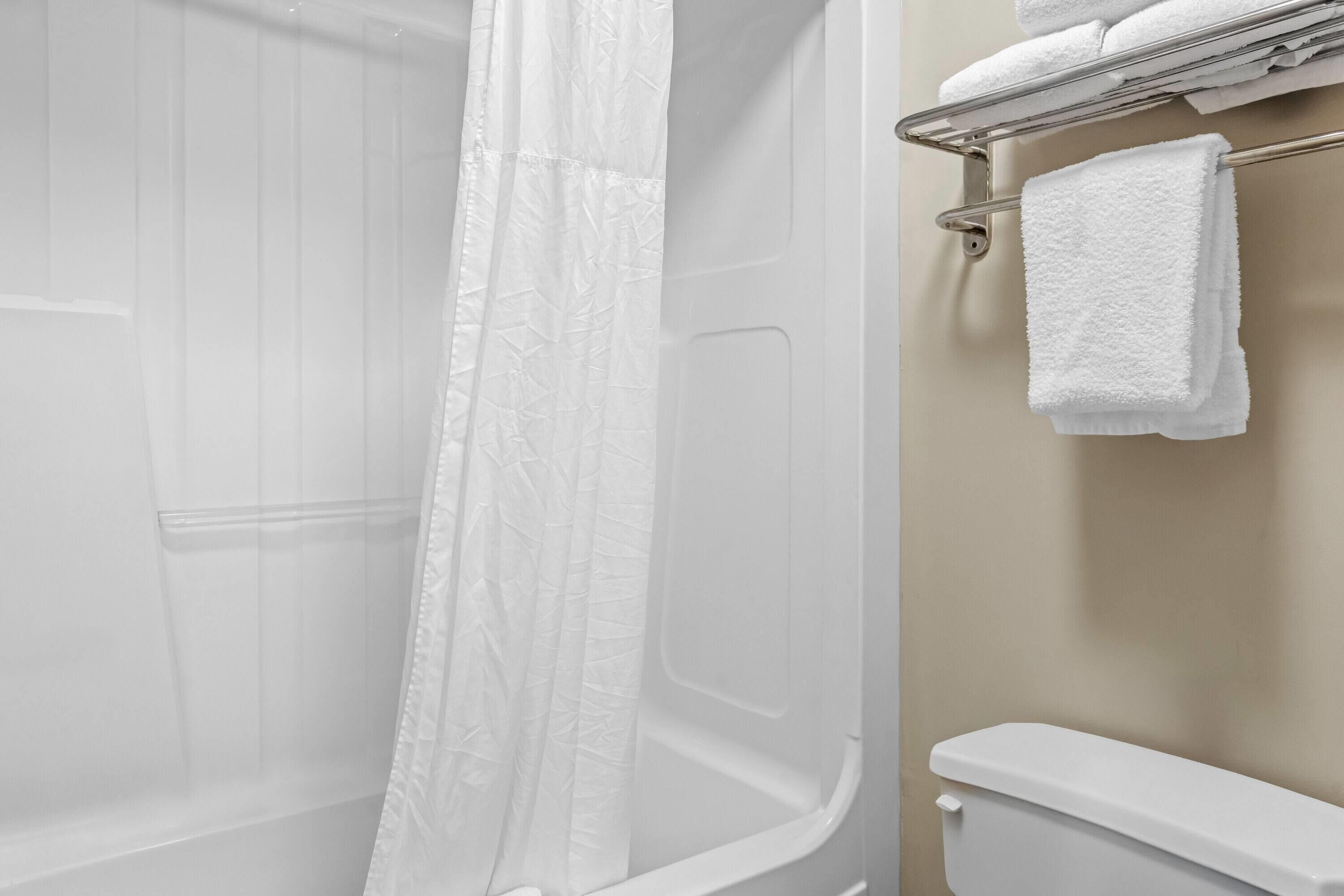 A bathroom with a shower curtain, a toilet, and a towel rack with towels.