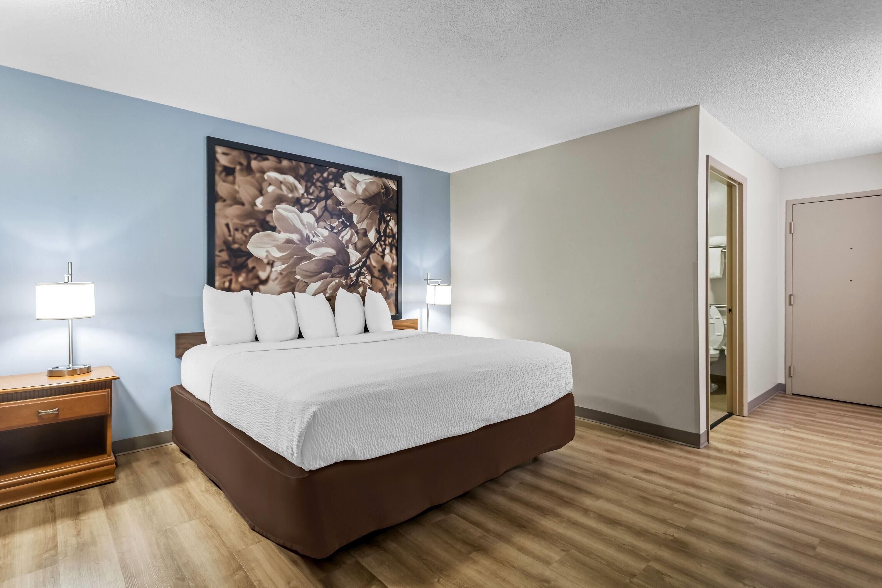 Una camera d'albergo con un letto grande, due comodini con lampade, un'ampia opera d'arte floreale sulla parete e un pavimento in legno.