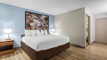 Una camera d'albergo con un letto grande, due comodini con lampade, un'ampia opera d'arte floreale sulla parete e un pavimento in legno.