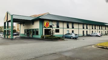 Un motel con fachada verde y blanca, un letrero de Super 8 y dos coches estacionados en el estacionamiento.