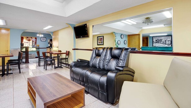 Un hall de hotel con un sofá de cuero, una mesa de centro de madera y una zona de comedor con sillas y mesas.