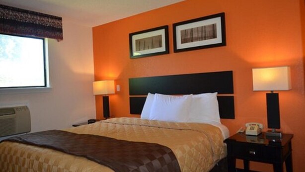 A hotel room with a bed, two bedside lamps, a nightstand with a telephone, and two framed pictures on the wall. - Enfield Inn (Enfield)