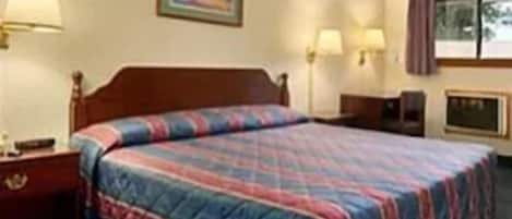 A hotel room with a bed, a nightstand, a lamp, a painting on the wall, and a window with curtains.