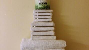 A stack of white towels arranged in a pyramid shape on a plain wall.