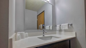 A bathroom with a white sink, a mirror, and two towels hanging on a towel rack.