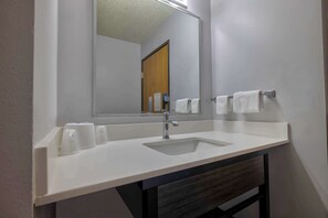 A bathroom with a white sink, a mirror, and two towels hanging on a towel rack.
