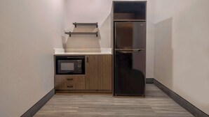 Una cocina compacta con microondas integrado, un mueble de madera y un refrigerador de acero inoxidable.