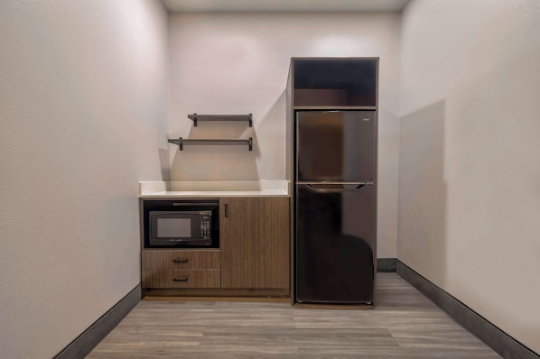 Una cocina compacta con microondas integrado, un mueble de madera y un refrigerador de acero inoxidable.
